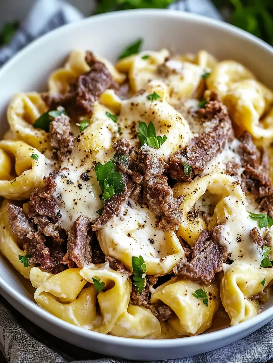 Un bol de pâtes garni de morceaux de bœuf, de fromage fondu, et parsemé de persil.