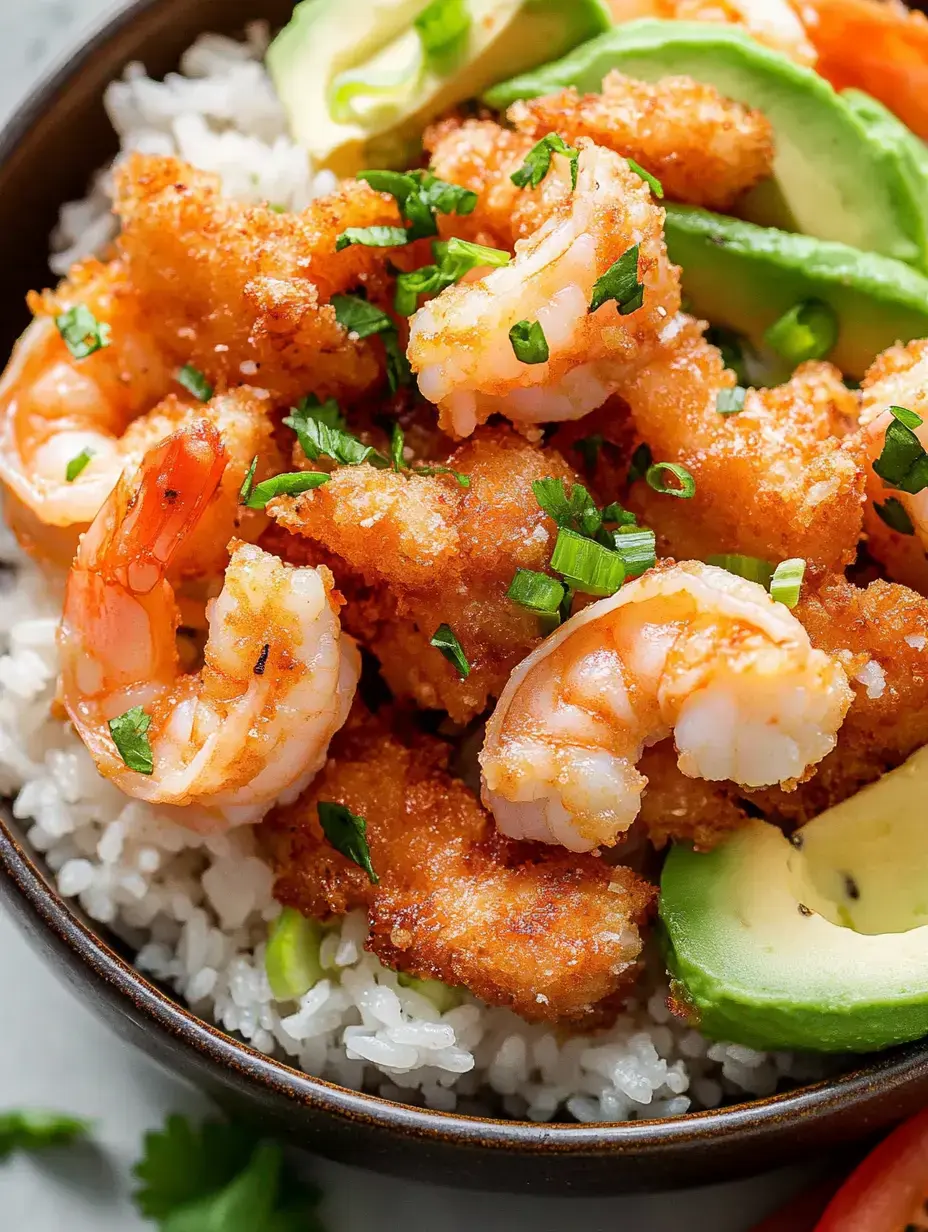 Un bol de riz blanc garni de crevettes frites croustillantes, décoré de ciboulette hachée et de tranches d'avocat.