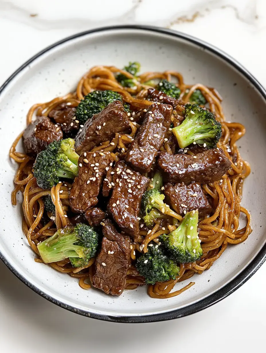 Un bol de nouilles sautées avec du brocoli et des morceaux de bœuf, garni de graines de sésame.