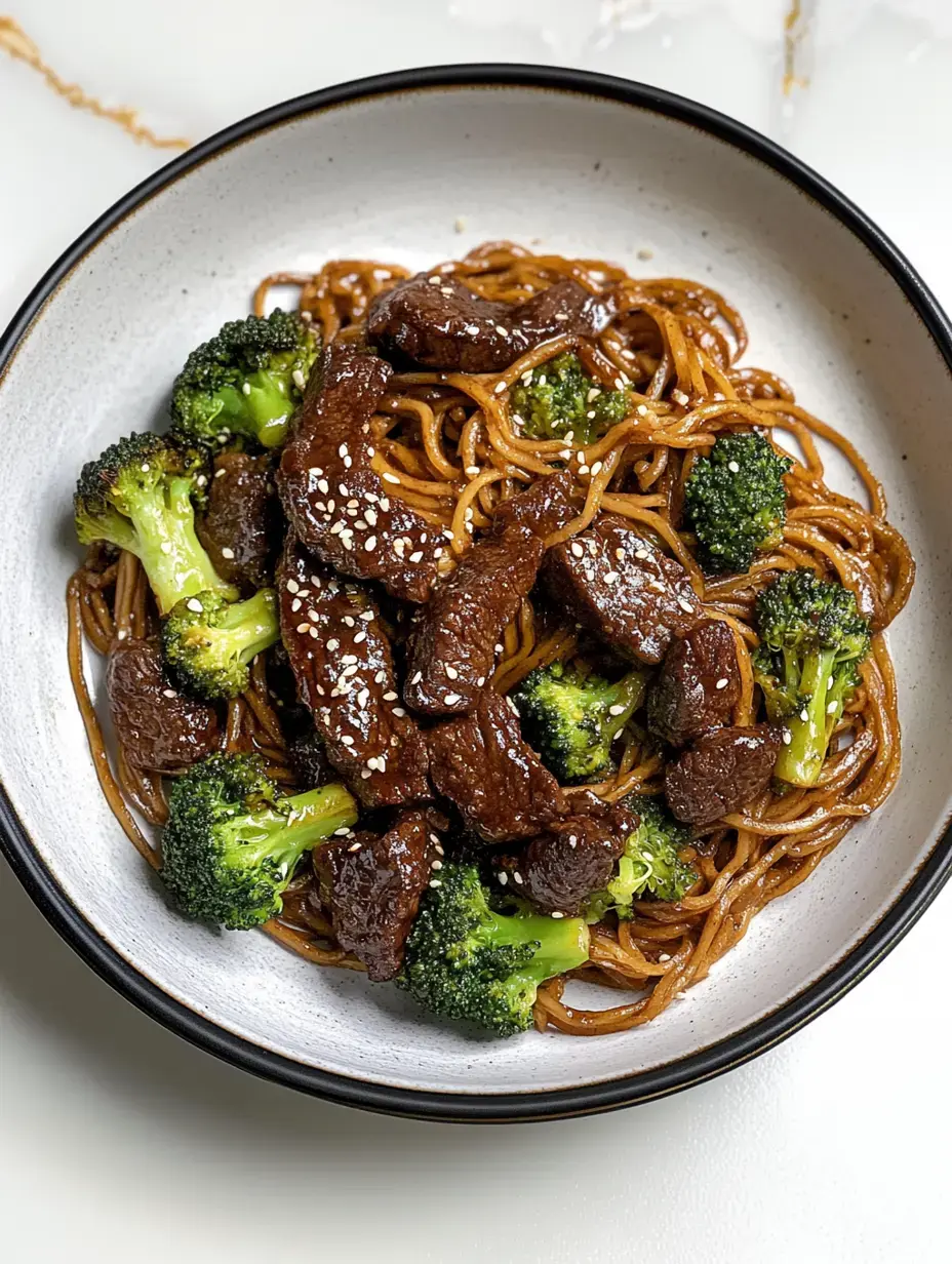 Un bol de nouilles garni de morceaux de bœuf et de brocoli, saupoudré de graines de sésame.